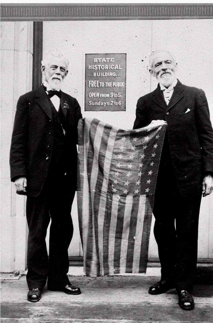 An undated photo taken at the Washington State Historical Society, Stevens (left), and Van Trump hold the flag they carried on their 1870 ascent.