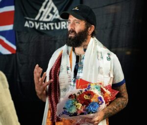 Hutchcraft holding a flower bouquet and wearing several khata scarves around his neck.