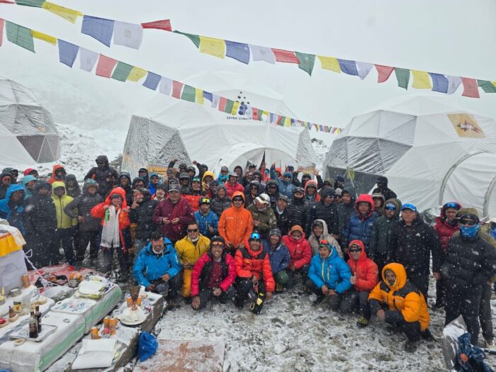 A big group at Everest Base Camp in a cloudy day, posing in front of the puja chorten. 