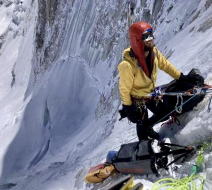 A climber at a belay station on a vertical mixed face