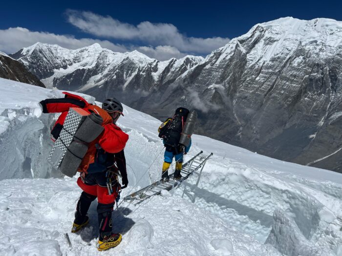 Climbers crossing a crevasse by an aluminium ladder, on Annapurna. 