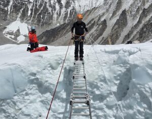 A sherpa crosses a big crevasse on Everest