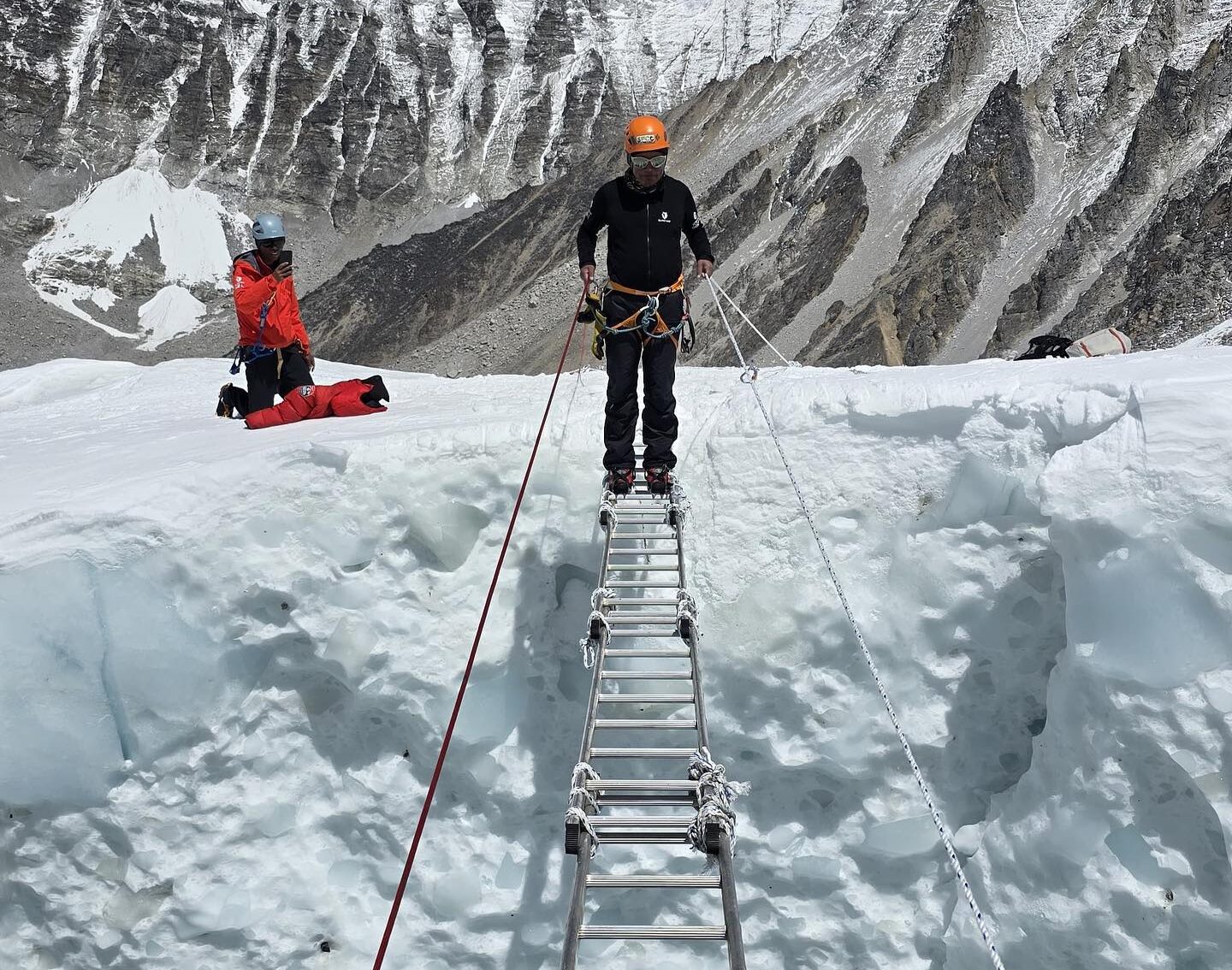 A sherpa crosses a big crevasse on Everest