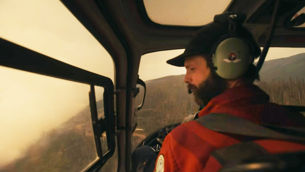 man in helicopter observes forest fire