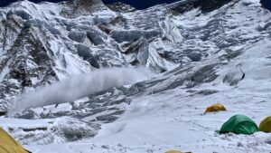 An avalanche on Annapurna, with some tents of Camp 2 in front.