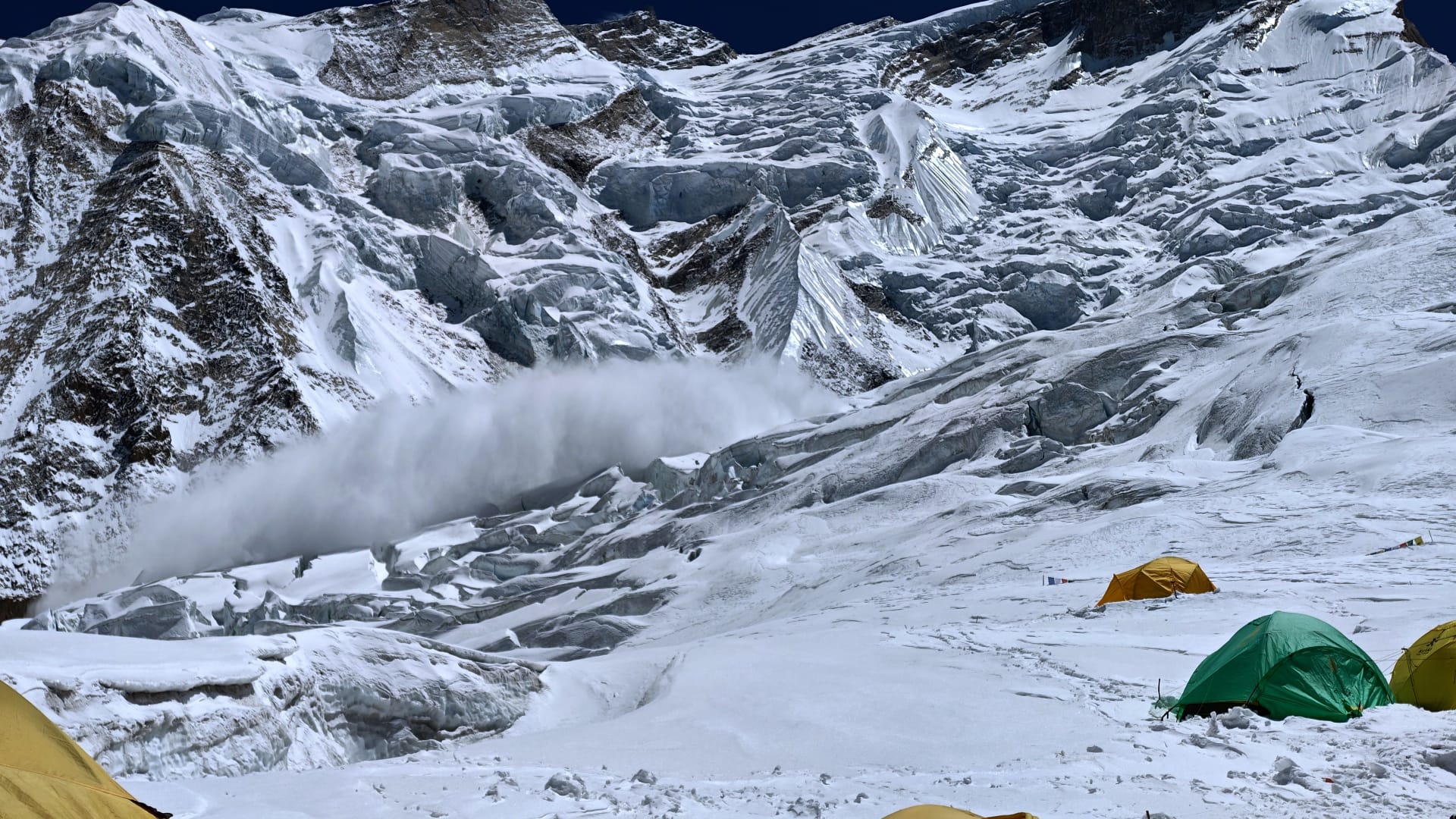 An avalanche on Annapurna, with some tents of Camp 2 in front.