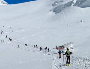 a small plane taxis between a close line of skiers