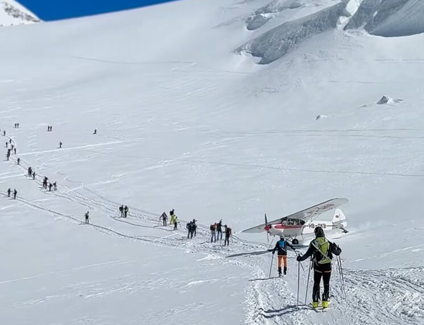 a small plane taxis between a close line of skiers