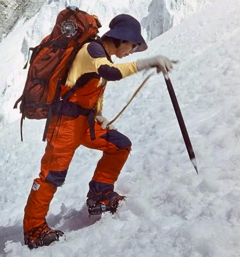 woman hiking on snow slope with ice ax