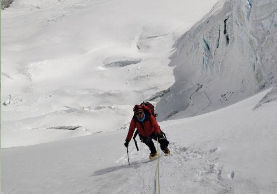 A climber clipped to fixed ropes on a steep snow slope with a serac at his side.
