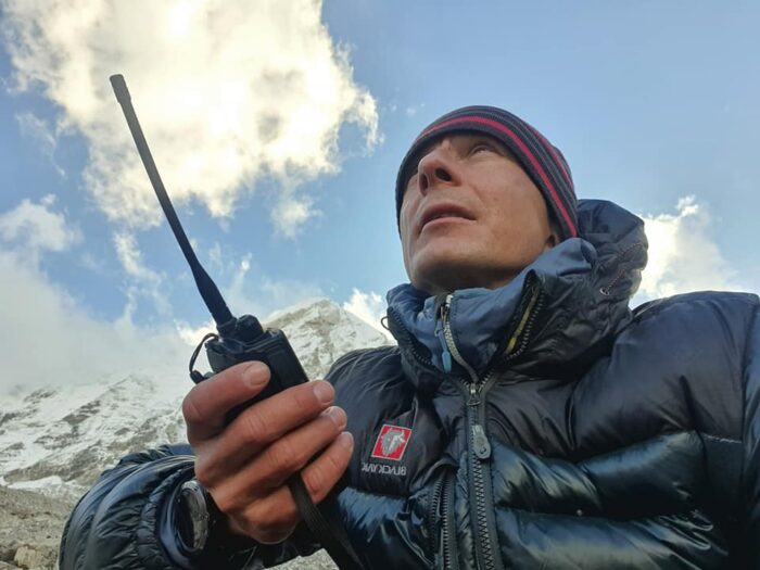 Expedition leader with a walkie-talkie in hand, looking up.