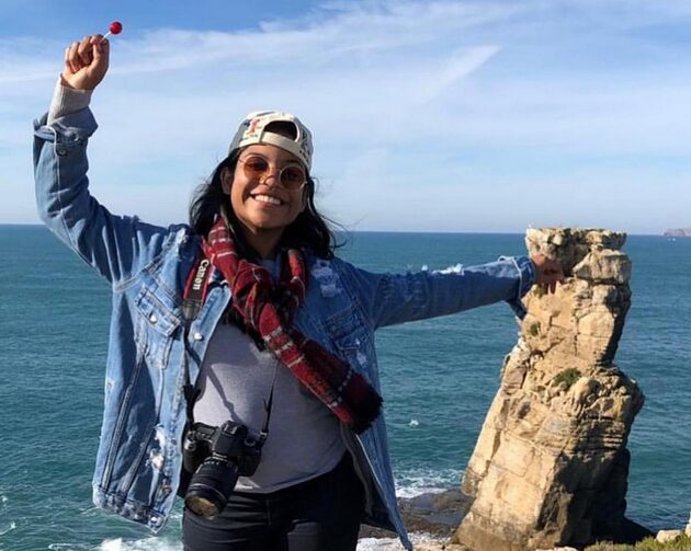 A young woman smiling by a rocky coast