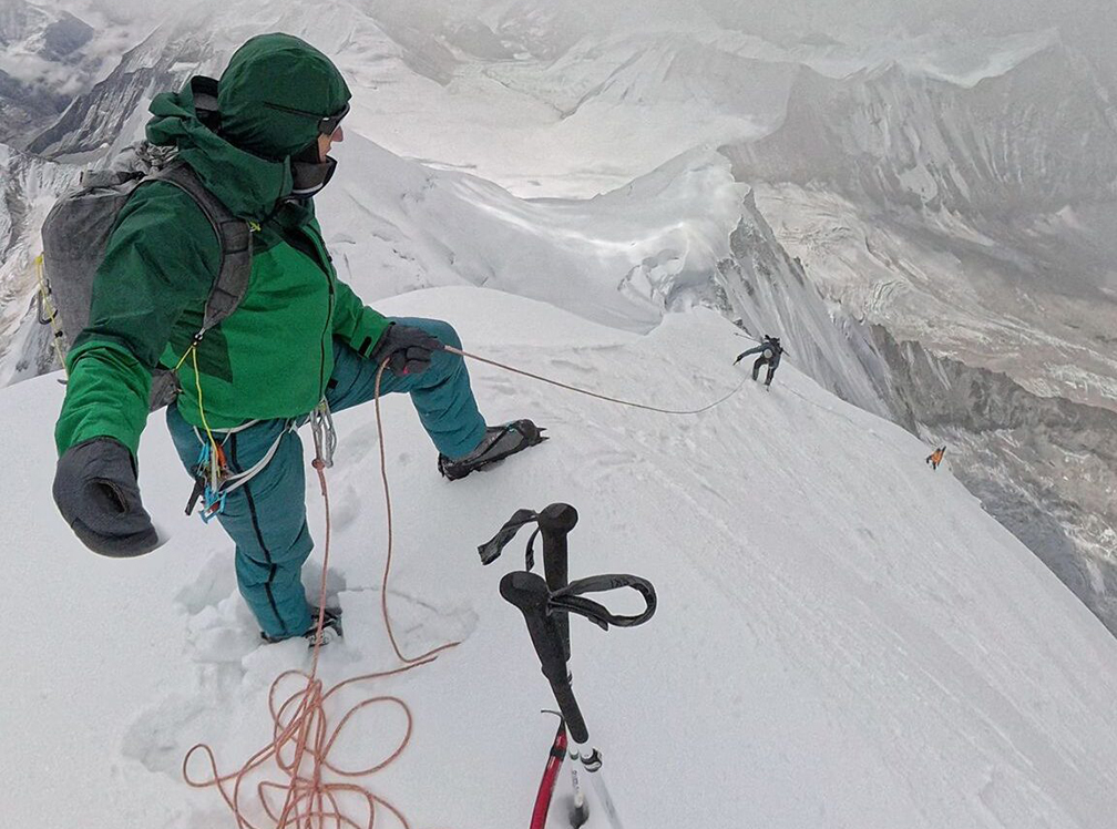 David Goettler on the summit of baruntse in a foggy day, with ice axe in the snow and rope.