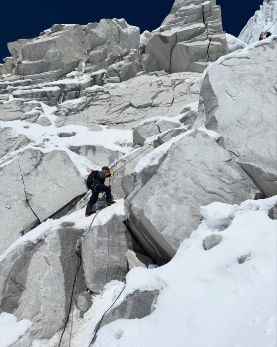 A climber progressing on a face of big blocks of rock 