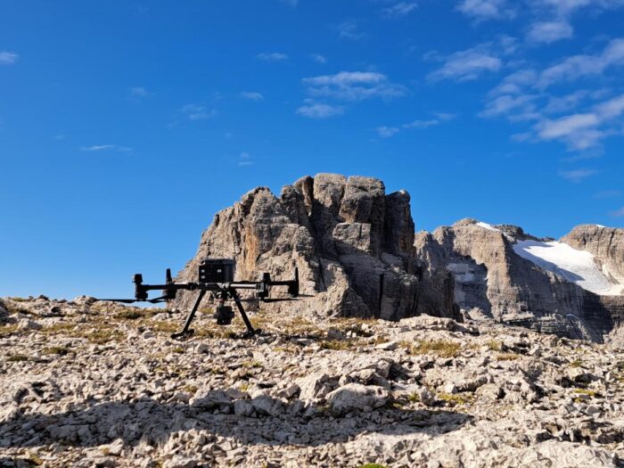 A drone posed on a flat summit area in the dolomites.