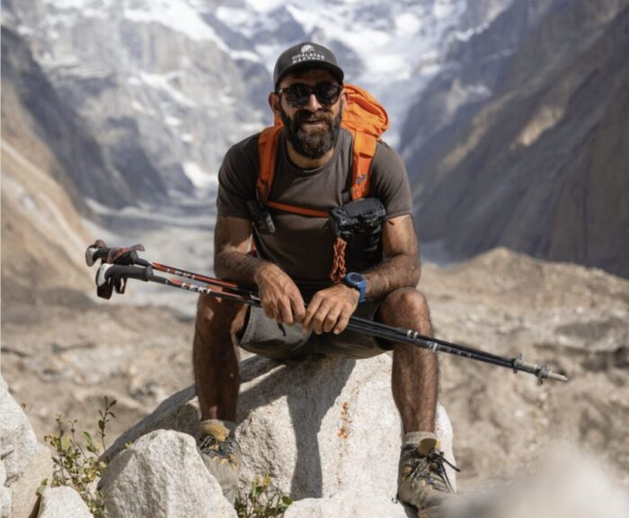 Sakhi with short trousers and trekking outfit, sitting on a rock.