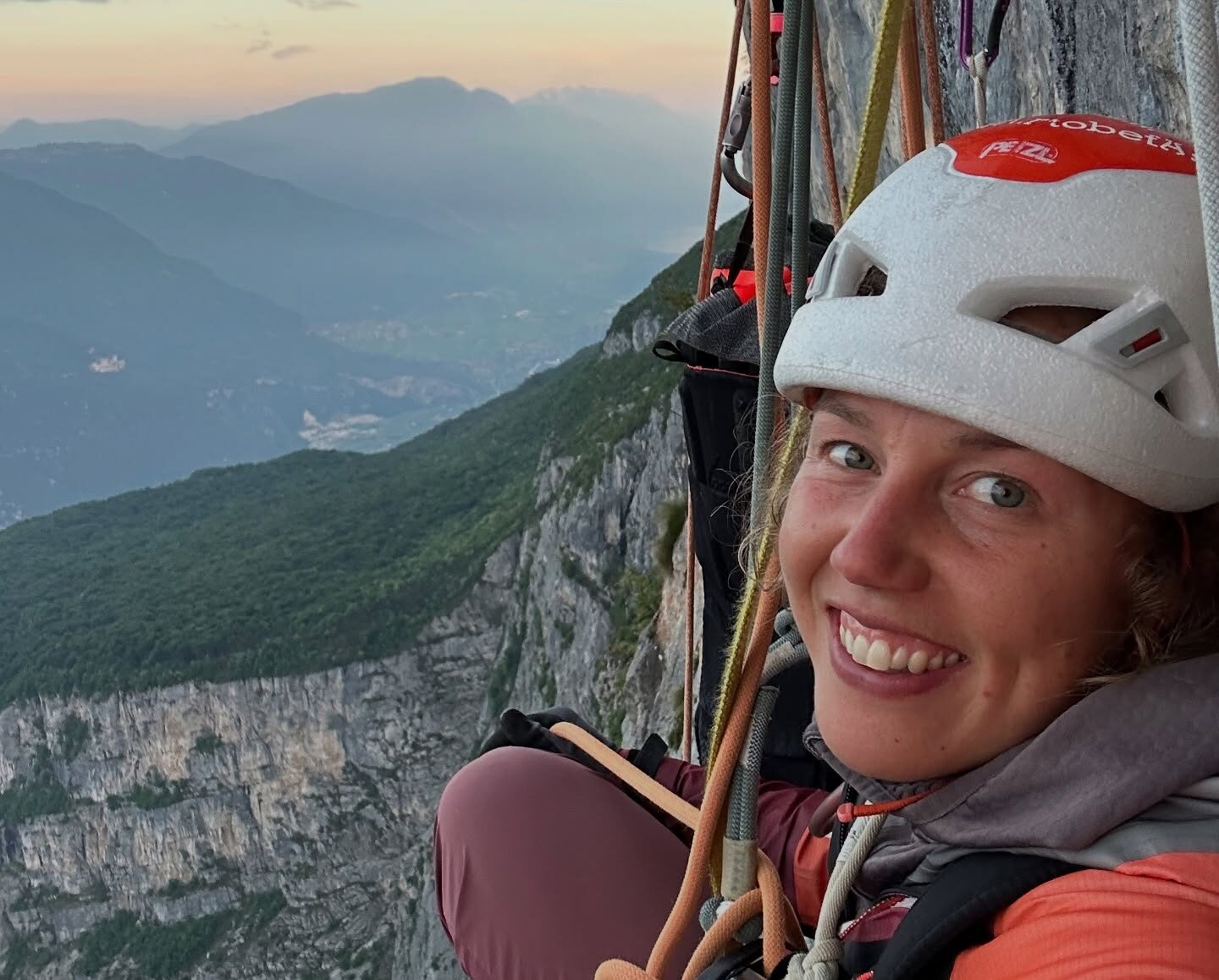 LAura Dahlmeier smiles from a ledge on a limestone wall in the Dolomites.