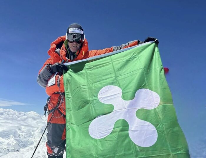 A climber with a big flag of Lombardia on a summit.