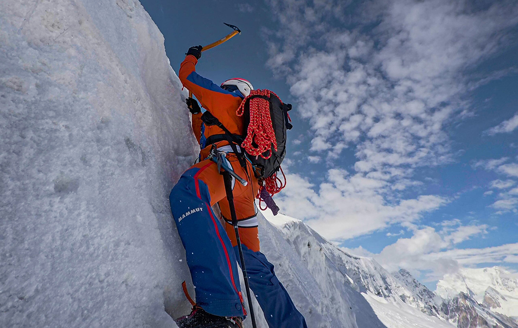 a climber gaining the top of a vertical ice section.