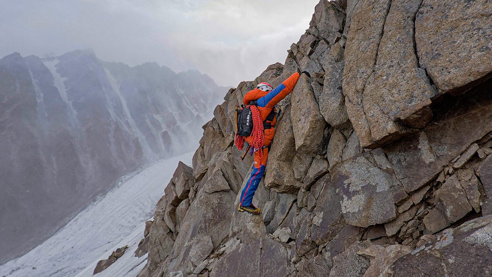 A climber downclimbing a ridge of rotten rock.