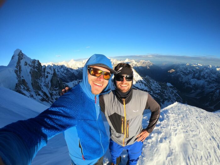 The climbers take a selfie on a mountain at dawn.