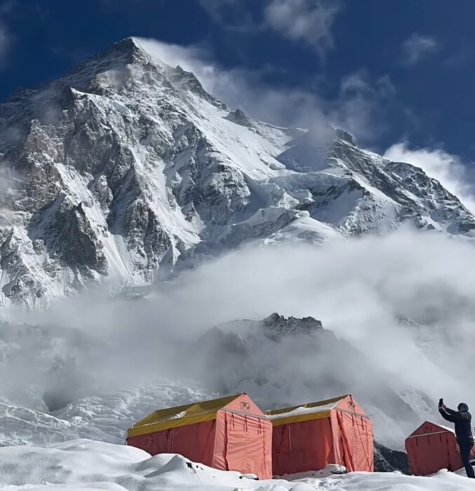 tents at the base of K2, with clouds around the mountain. 