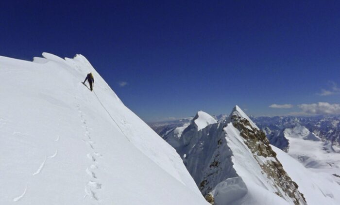 a cvlimber on a steep, corniced snow ridge.