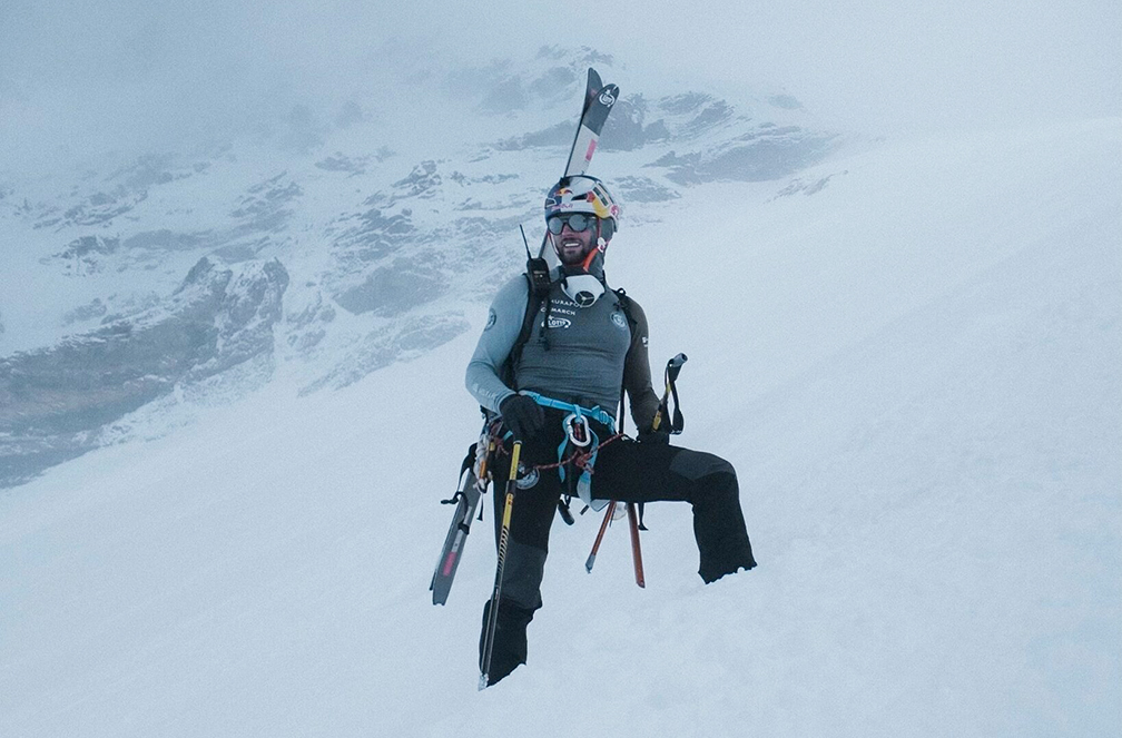 Bargiel on Everest, feet sunk in fresh snow and skis on his back, in a foggy day