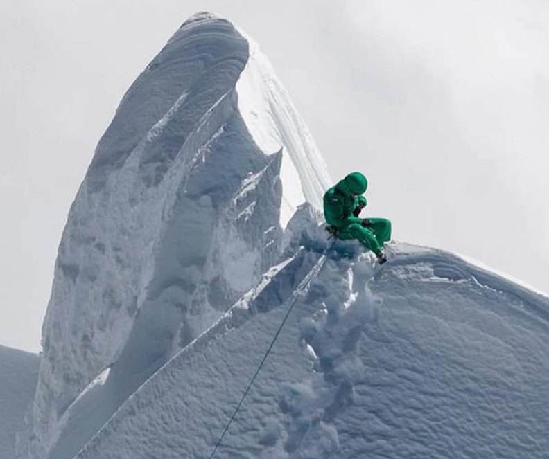 climber beside sharp snowy peak