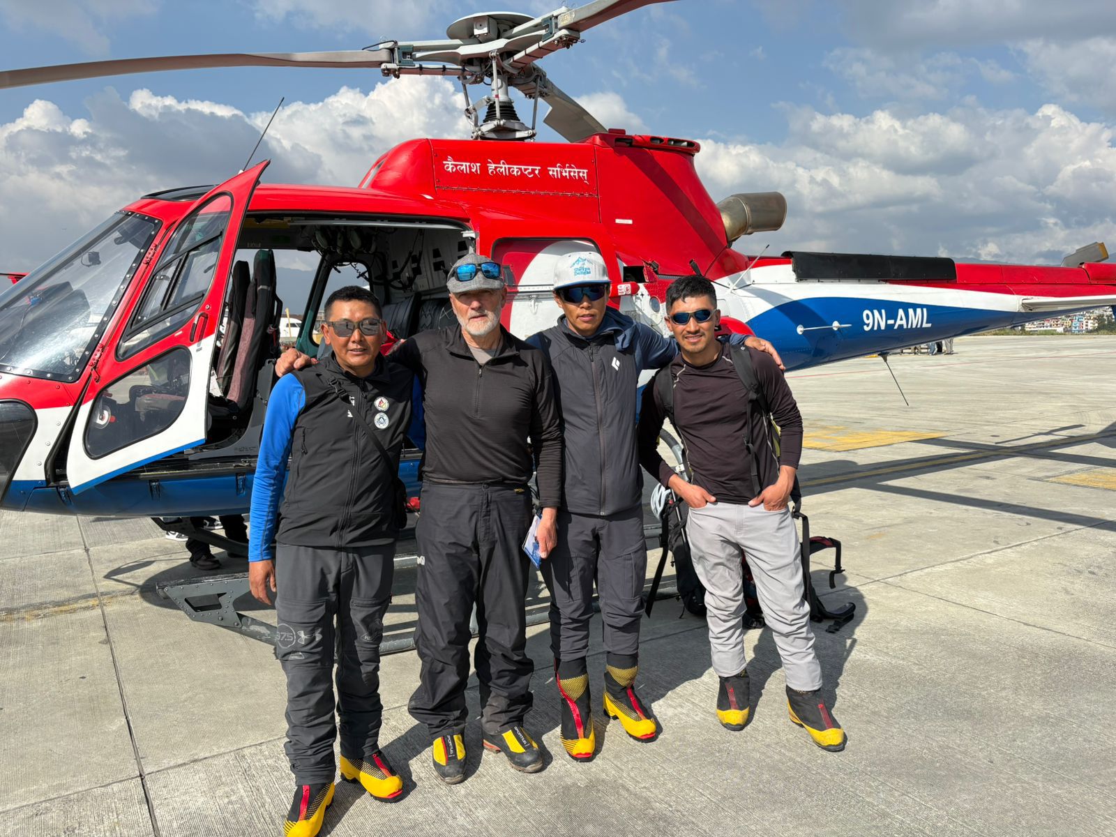 Four people in front of a helicopter.
