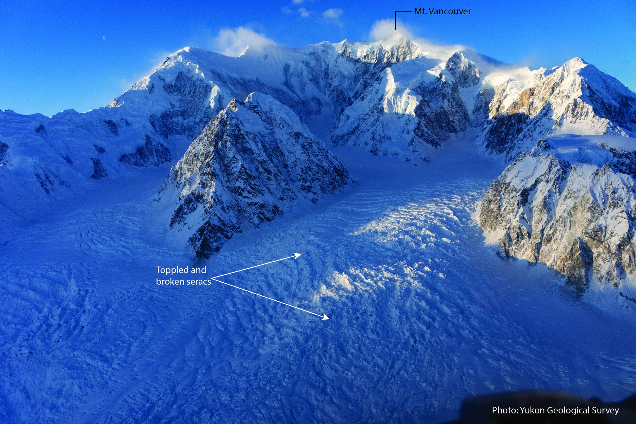 A photo of mountains with a crumbled ice field beneath.