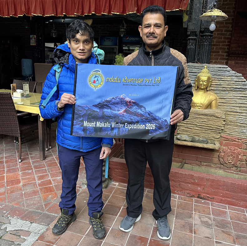 Climber and outfitter in a hotel in Kathmandu posing with an expedition banner.