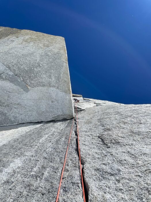 A climber on vertical granite in the sun.