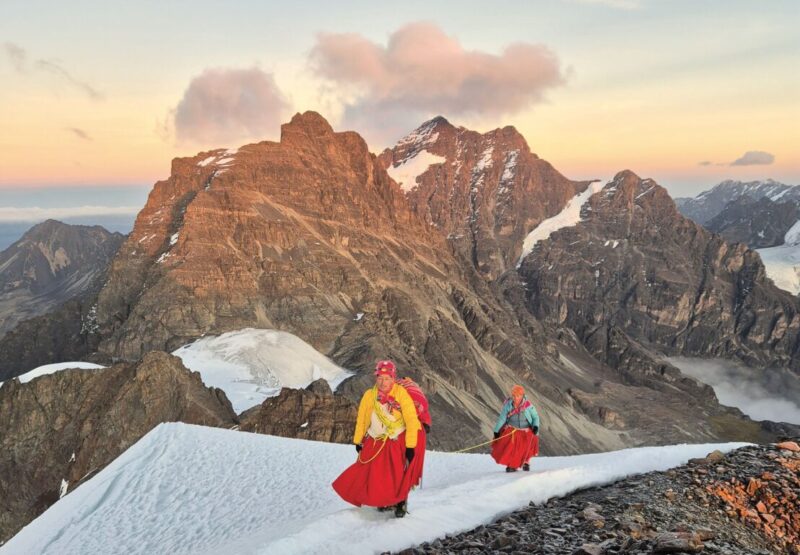 Bolivian cholita climbers ascending Pequeño Alpamayo at sunrise