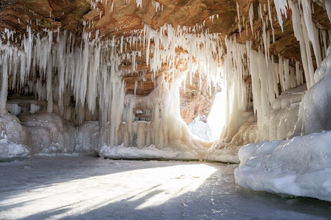 A photo from inside the Apostle ice caves, showing hundreds of long icicles hanging from the roof of the cave. 