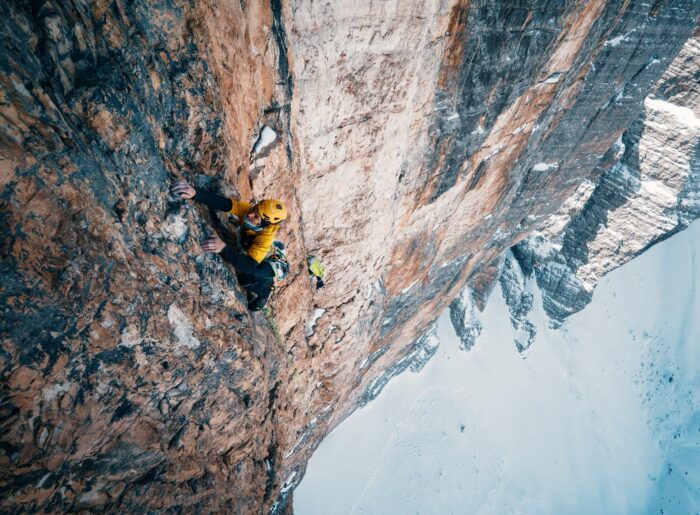A climber soloing the vertical north face of the Cime Grande di Lavaredo.