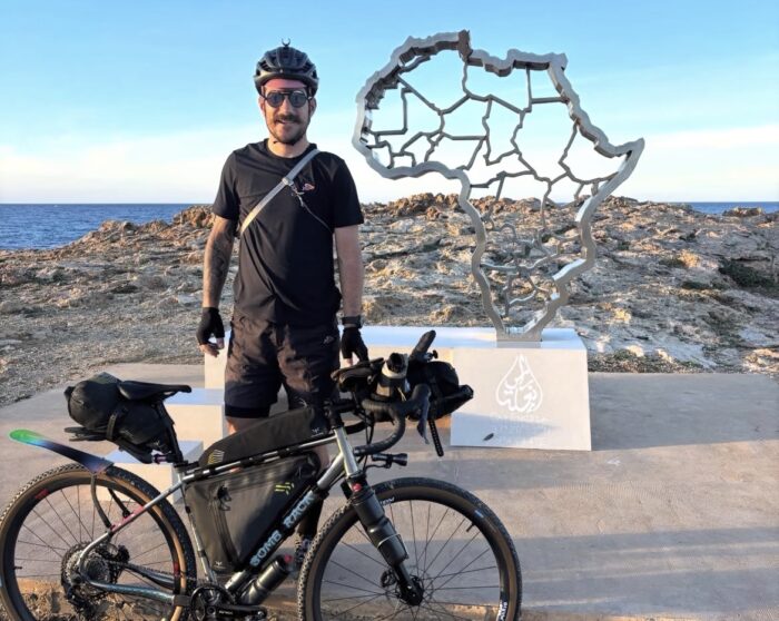 Swiss cyclist Adrien Liechti standing with his bike at  Cape Angela in Tunisia. 