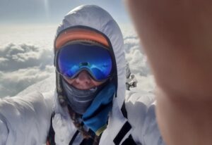 Selfie of Peter hamor with hood and goggles and a sea of clouds behind.