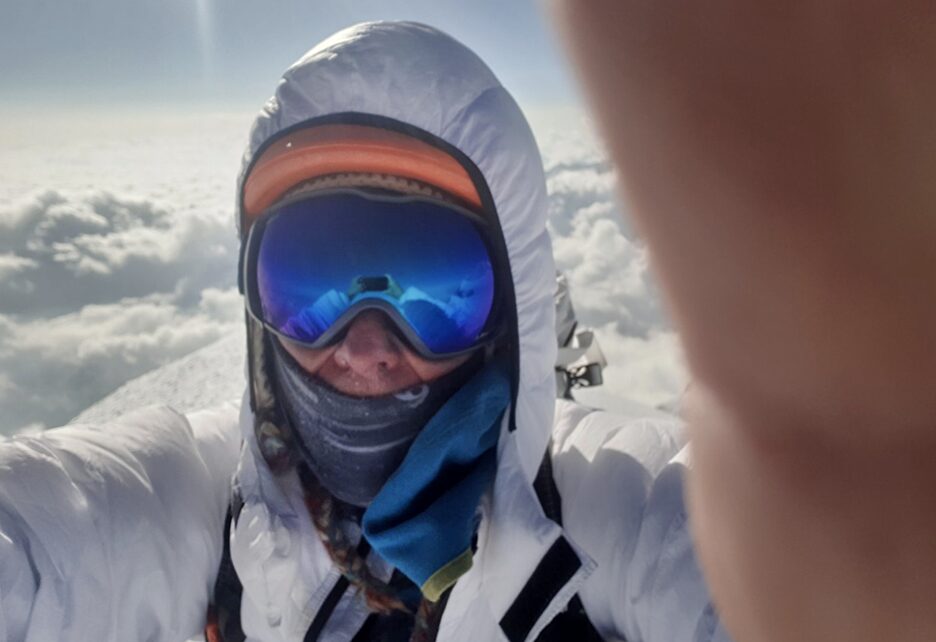 Selfie of Peter hamor with hood and goggles and a sea of clouds behind.