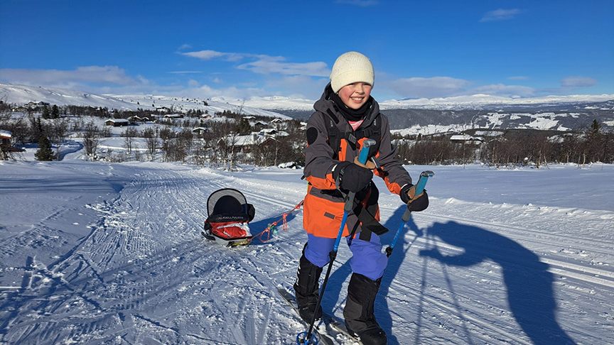young girl skiing and pulling sled