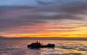 Chris Barbin starts his Pacific crossing, the photos shows his boat silhouetted against a sunset as he rows.