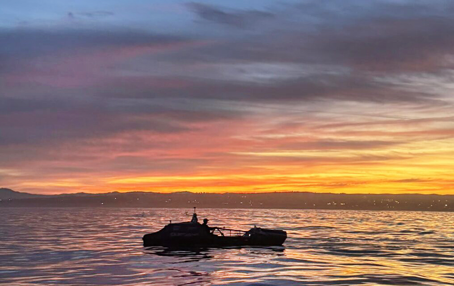 Chris Barbin starts his Pacific crossing, the photos shows his boat silhouetted against a sunset as he rows.