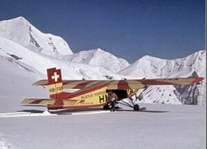 yellow aircraft on snow amid mountains