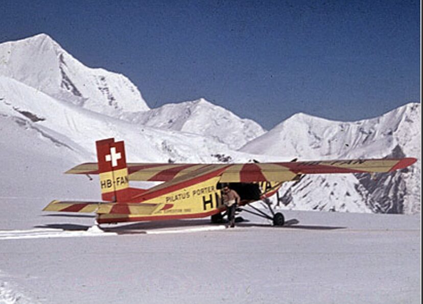 yellow aircraft on snow amid mountains