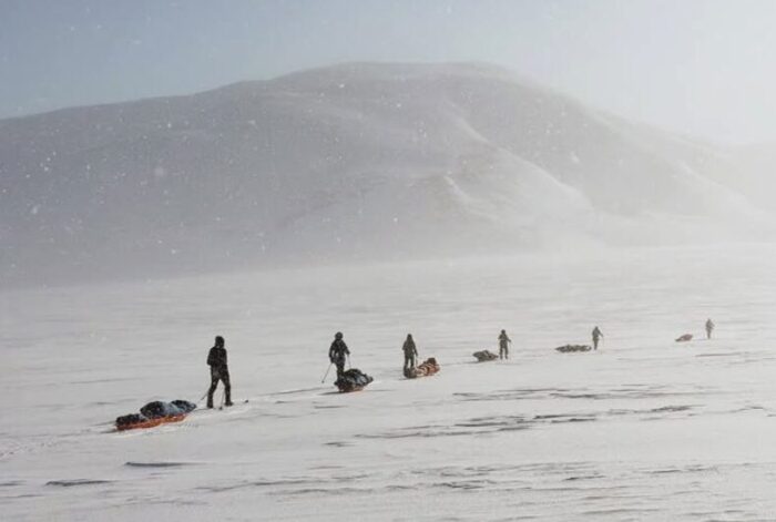 Four adventurers haul sleds on Svalbard