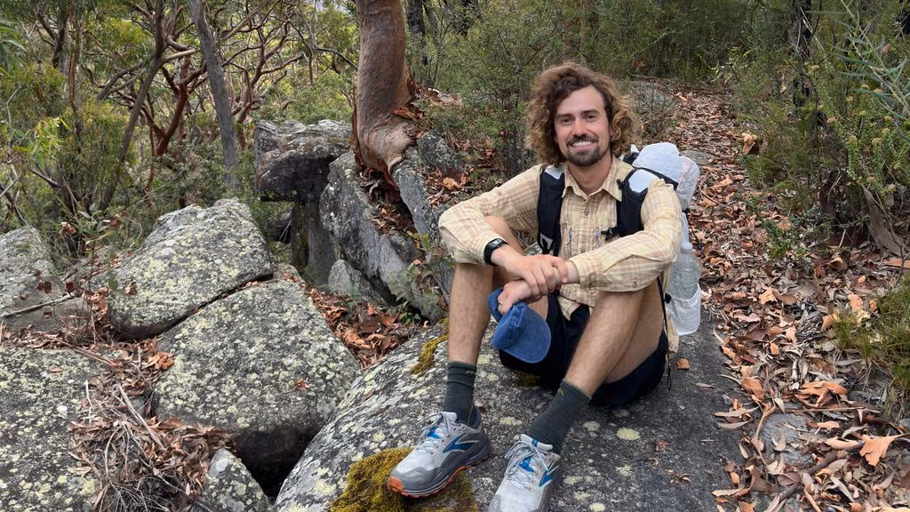 guy with backpack sitting down in the woods