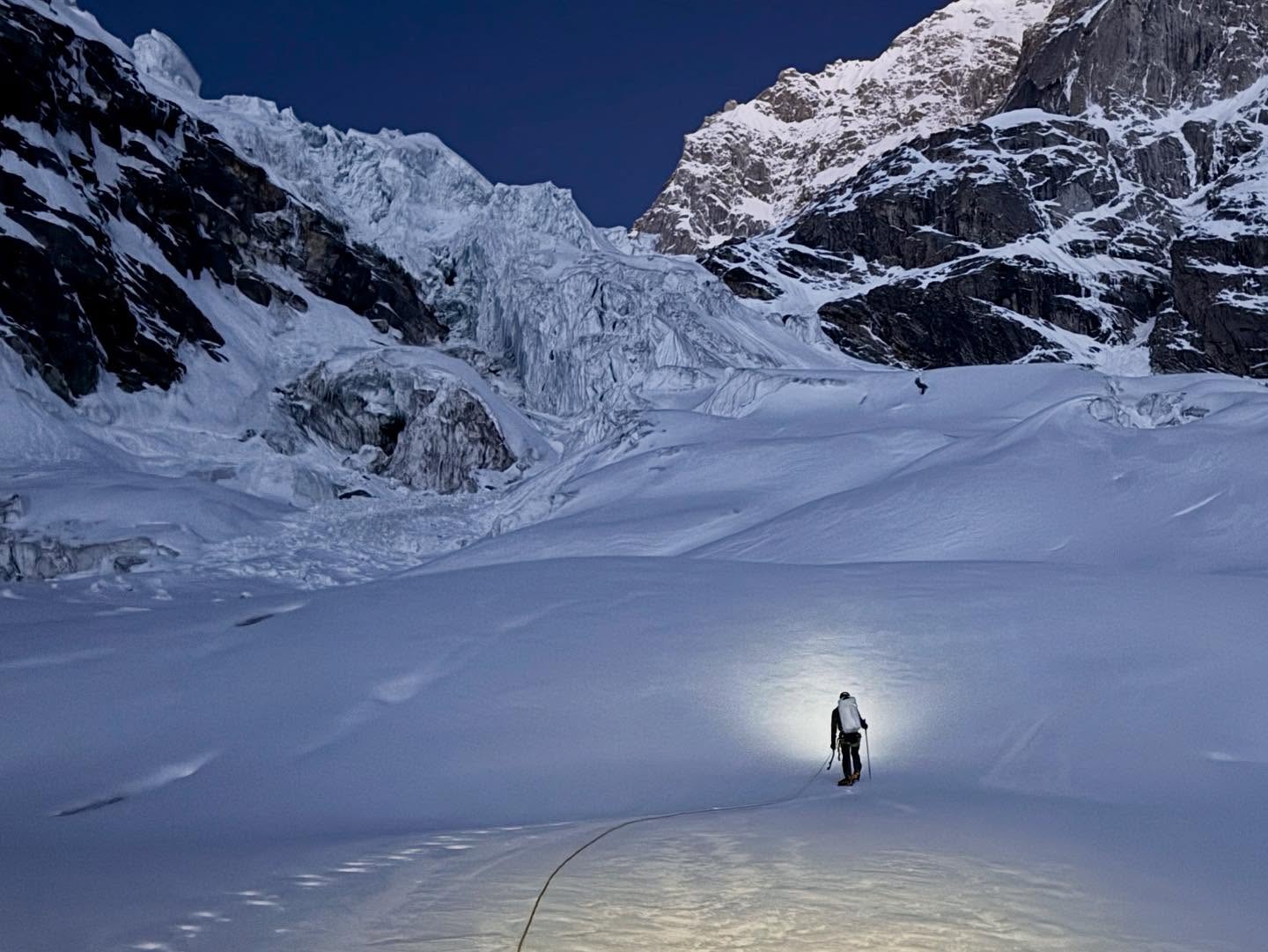 A lonely climber on a glacier, with an icefall marking a col between to mixed mountain faces.
