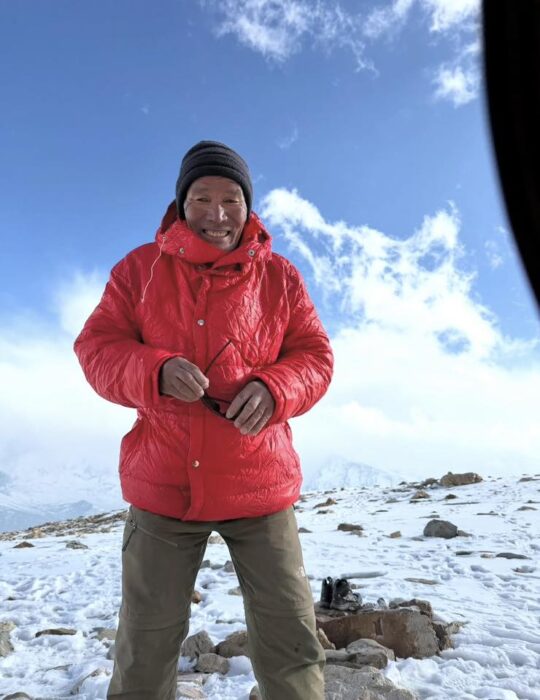 Close shot of a Sherpa climber with a wooden cap and a red jacket.