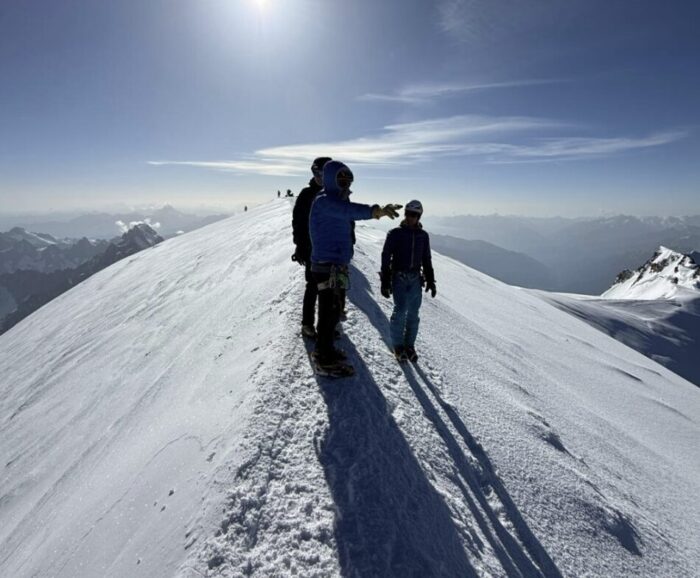 A climber points to some peak from the summit of Mont Blanc.