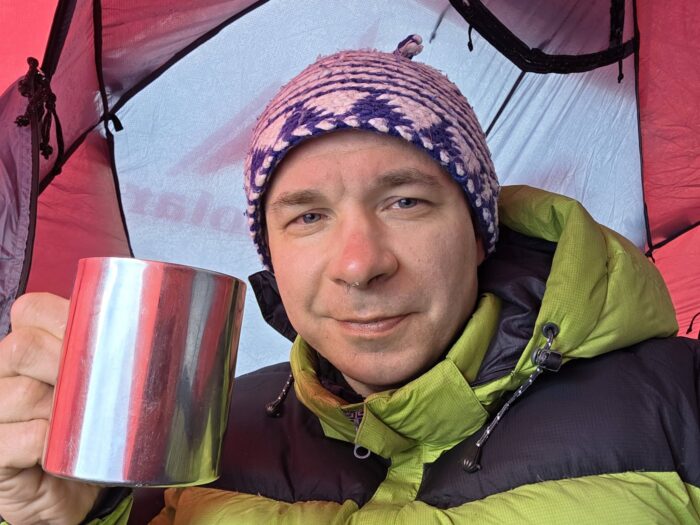 Close shot of Mariusz Chmielewski with a tin cup in a tent.